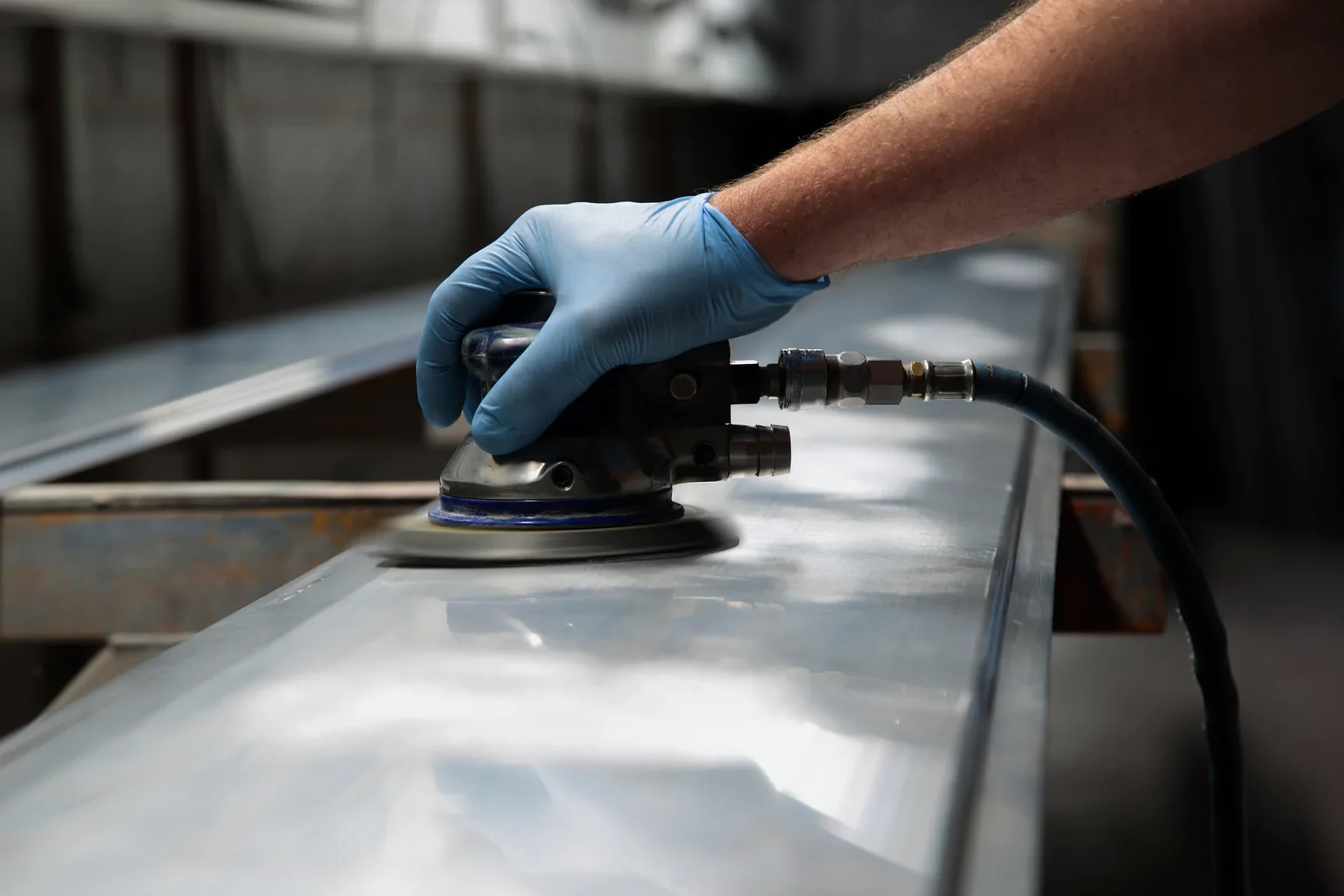 Orbital sander working along a metal panel